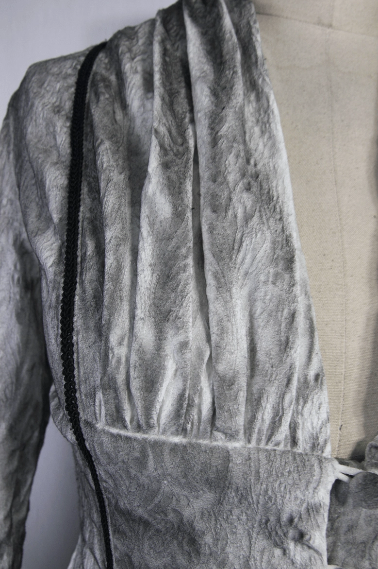 Close-up detail of white gothic blouse deep V-neckline with black vertical trim and draped chiffon