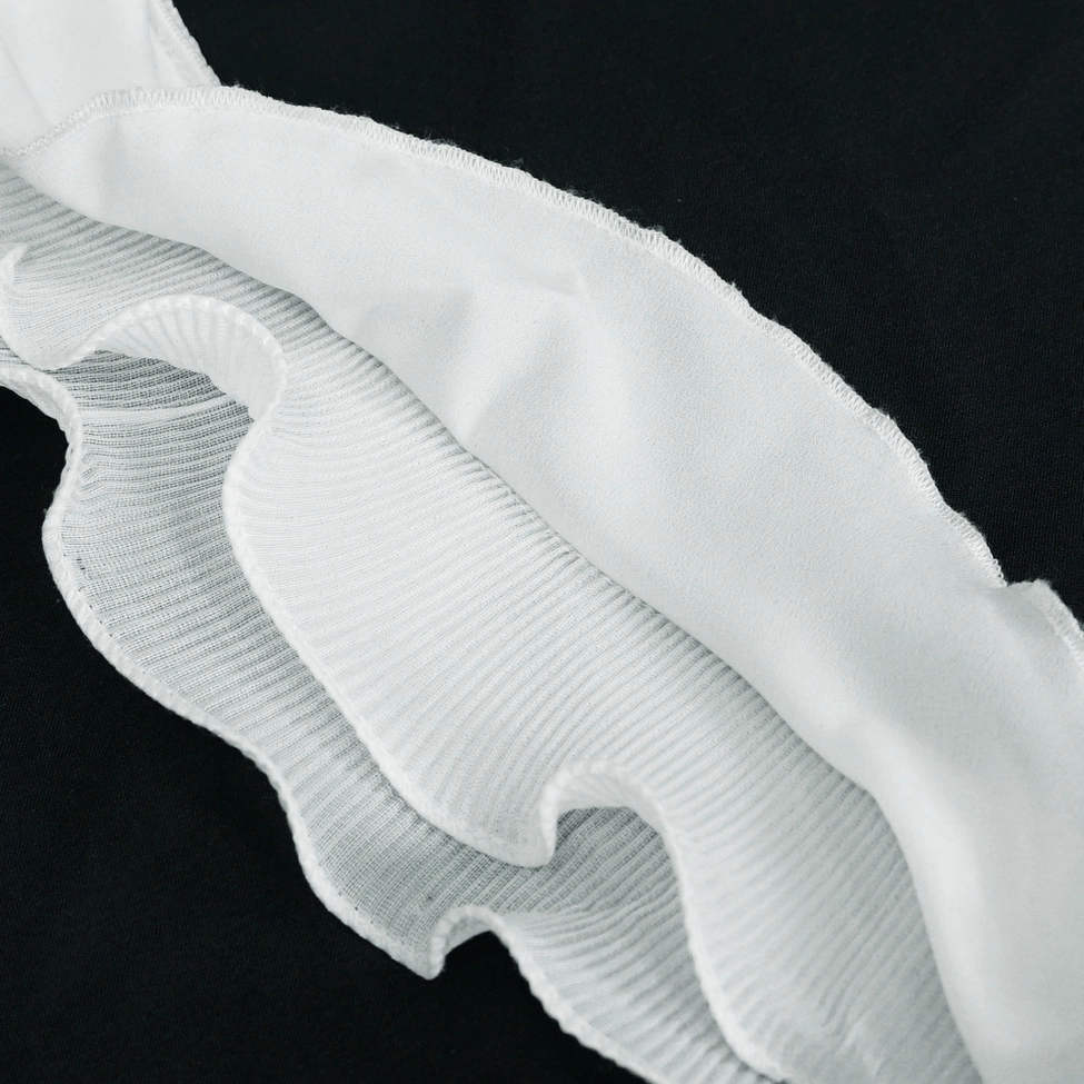 Close-up detail of white gothic blouse showing floral embroidery design and wavy ruffle construction