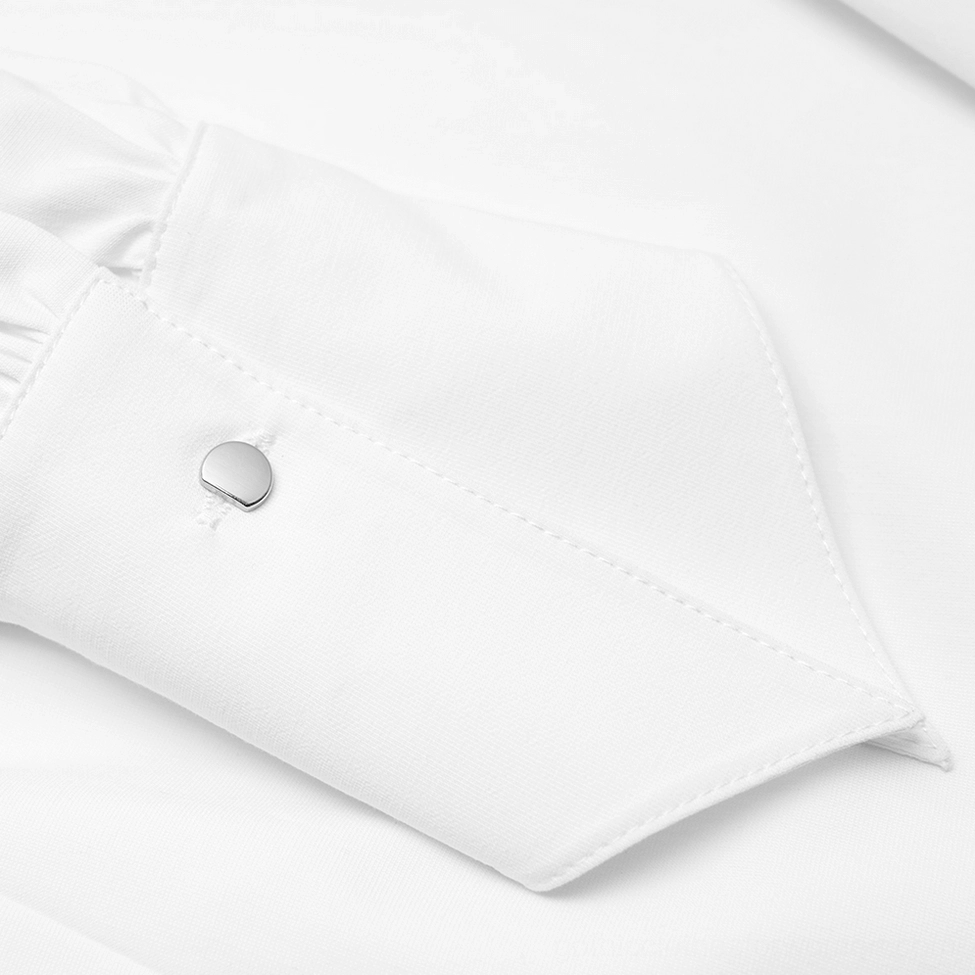Close-up macro shot of metal round cuff button and precise stitching on white gothic shirt dress, showcasing craftsmanship details