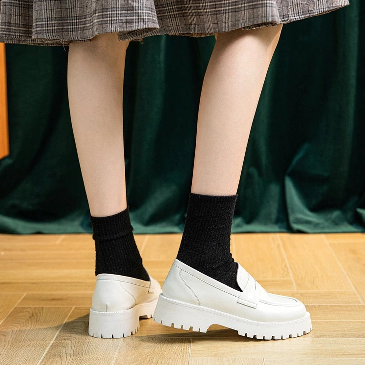White slip-on leather loafers on model, rear low-angle view showing heel construction and comfortable fit