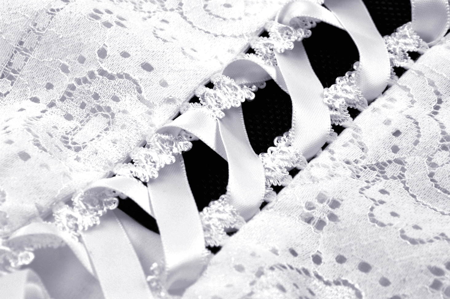 Side close-up view of white lace gothic dress highlighting lace-trimmed ribbon lace-up detail and embroidered floral fabric