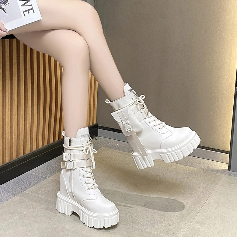 Woman's legs in white platform combat boots with lace-up and lug sole against wooden panel wall