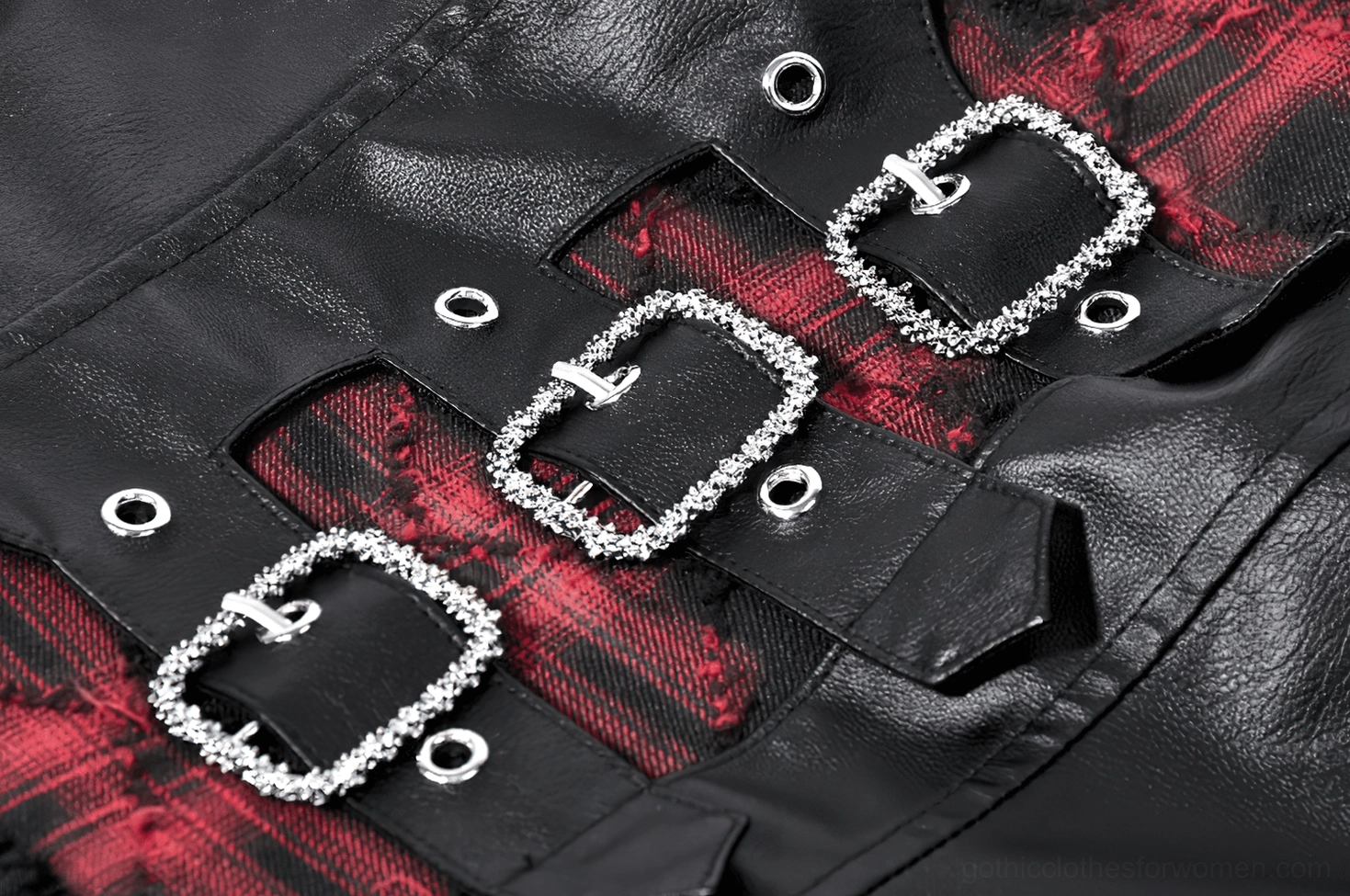 Close-up detail of sparkling rhinestone buckle borders on faux leather corset strap of gothic tartan dress showing metallic accents