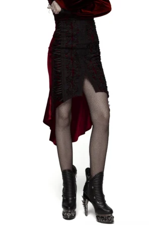 Front angle view of wine red velvet gothic fishtail skirt with rose lace panel worn by model, showing dramatic high-low hem with asymmetrical split and platform boots