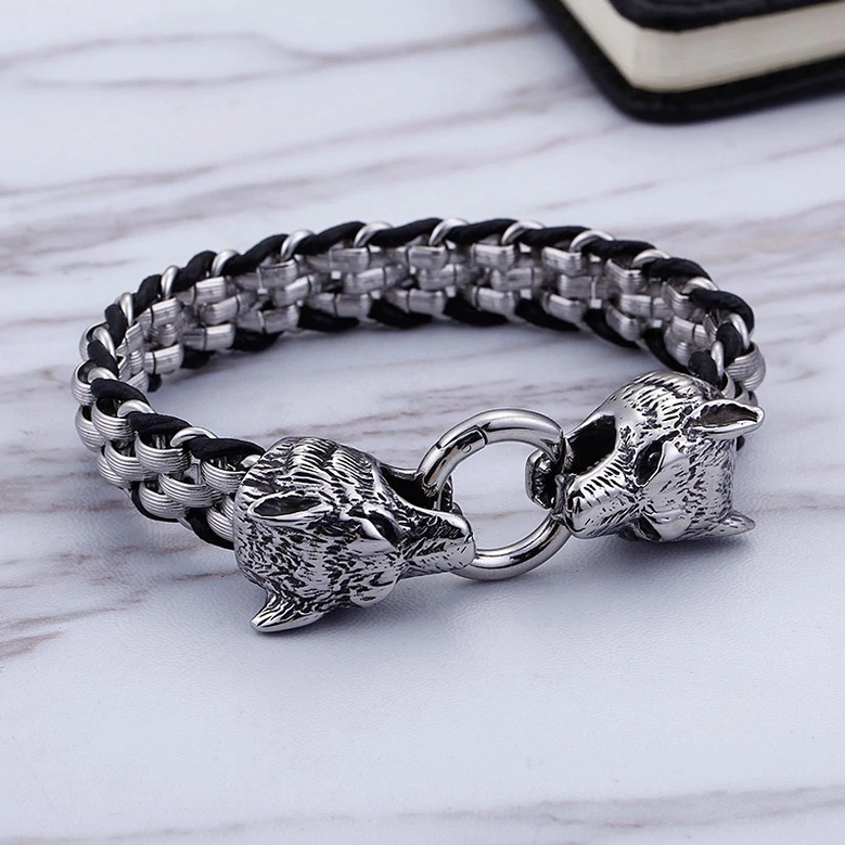 Flat lay of gothic wolf head bracelet on marble surface showing braided chain and dual wolf clasp design