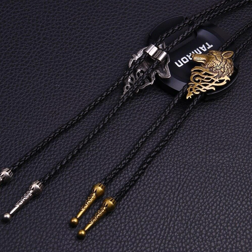 Wolf head gothic necklaces flat lay on leather background showing black rope chain and metal hardware details