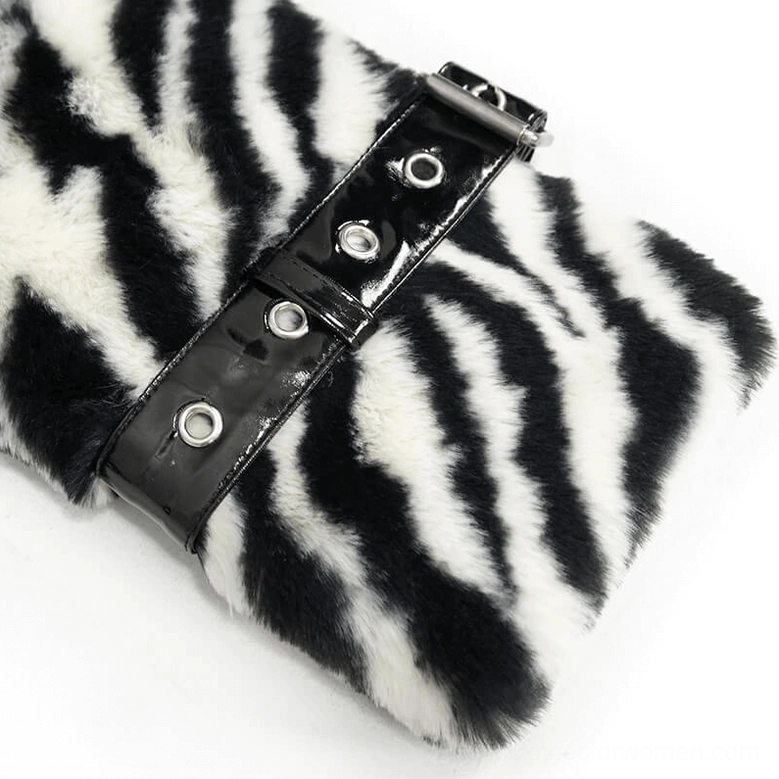 Close-up macro view of zebra faux fur jacket cuff strap detail with patent leather buckle and metal eyelets on fluffy fur fabric